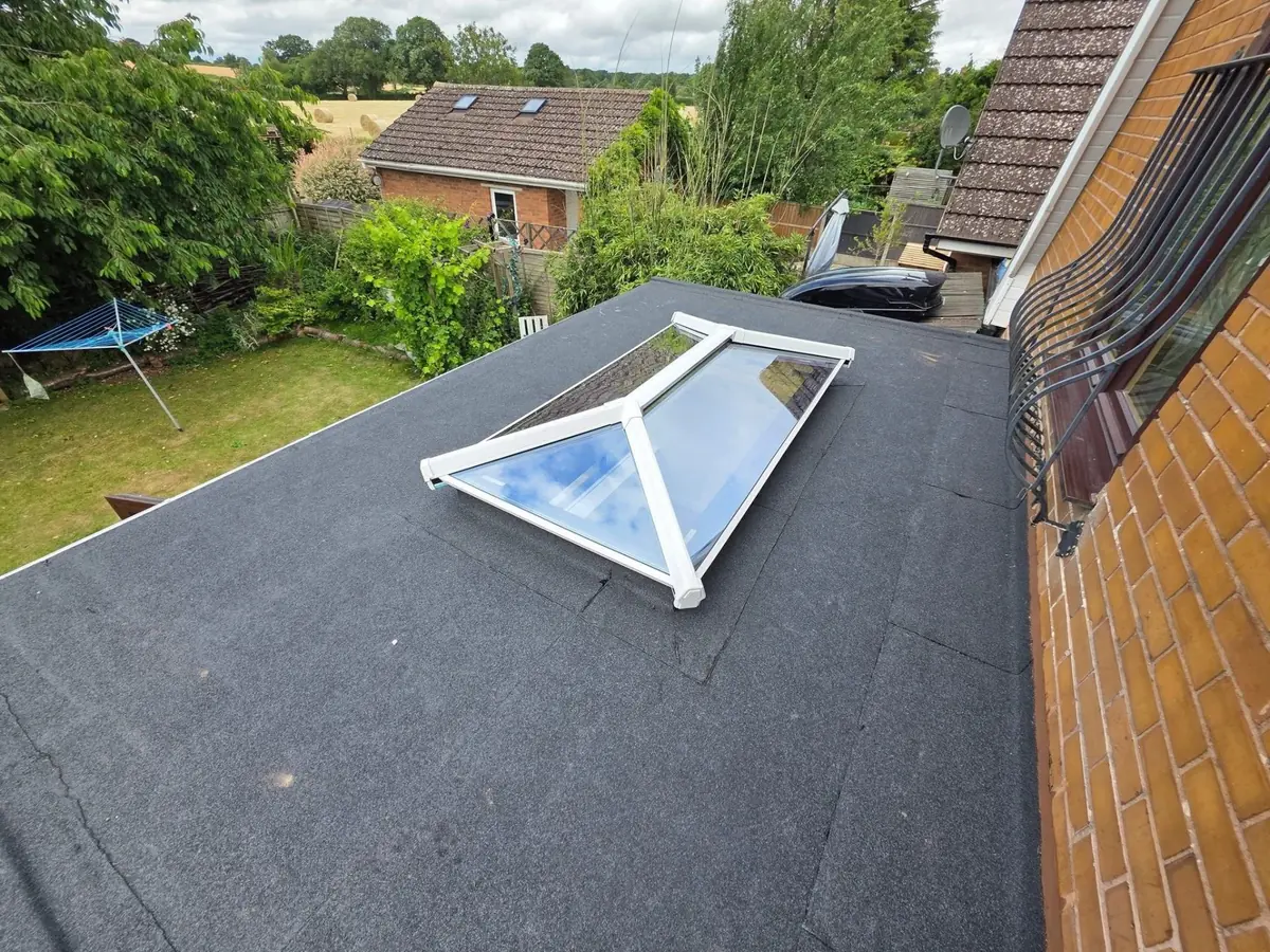 Felt flat roof and roof lantern viewed across the garden, showing fall and edge trim