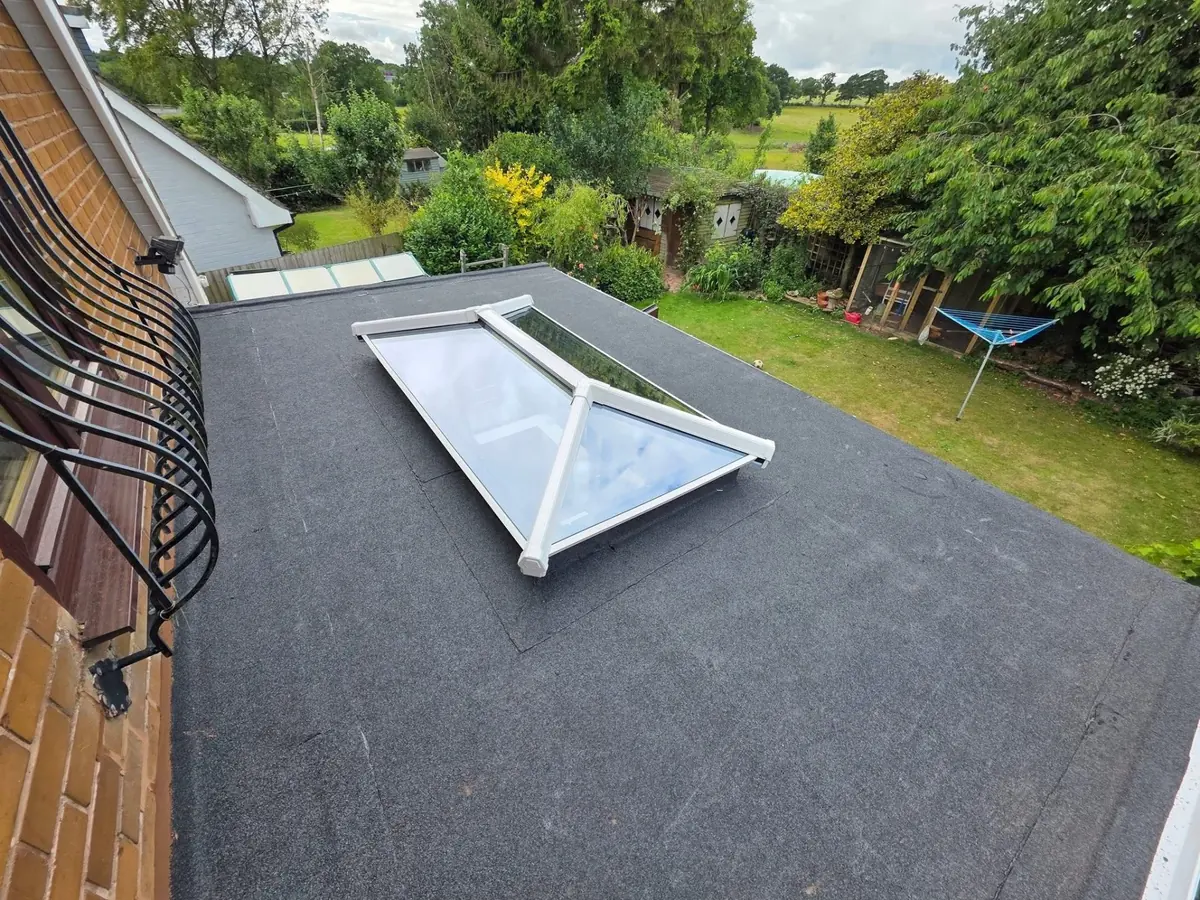 Wide angle view of completed felt flat roof installation with roof lantern overlooking the garden