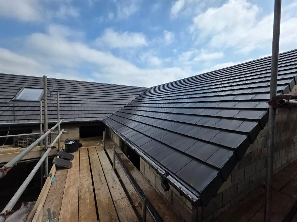 Hip junction on a new build tiled roof showing scaffolded eaves and clean ridge line