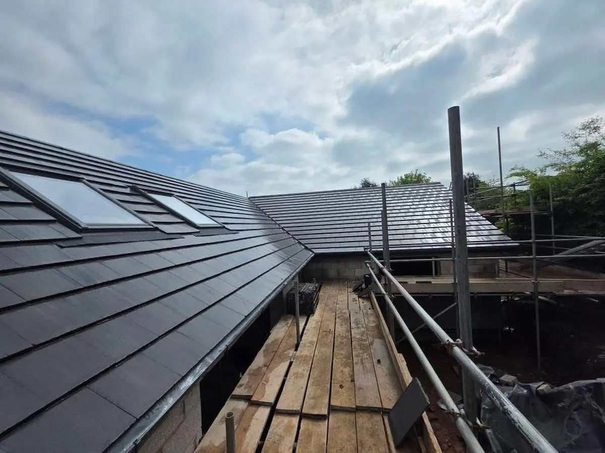 Tiled valley junction on a new build roof where two pitches meet, with Velux windows beyond