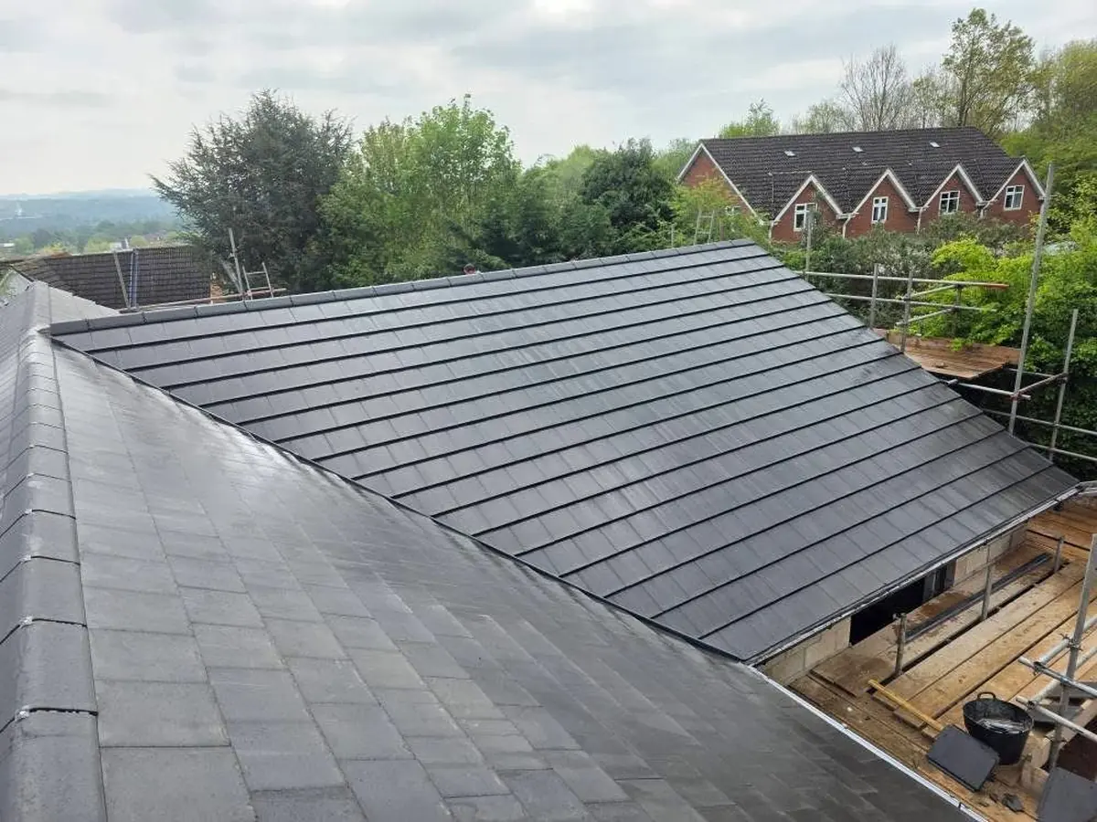 Newly tiled multi-pitch new build roof in graphite concrete tiles with felt ridge undercloak