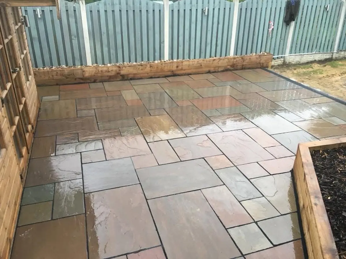 Riven Indian sandstone patio with raised sleeper planters and trellis screening