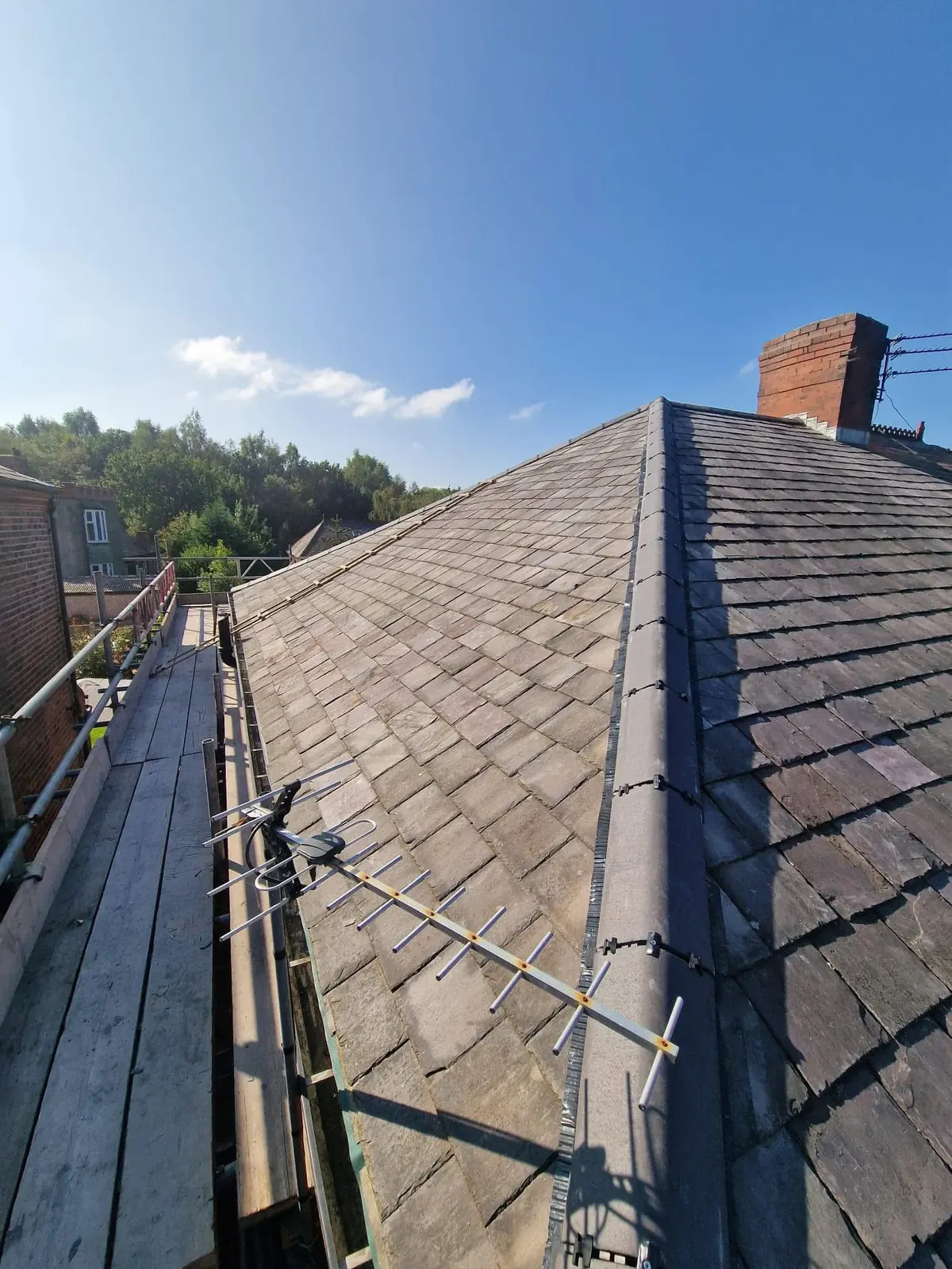 Side view of a slate roof from scaffolding showing fresh hip detail and antenna re-fixing