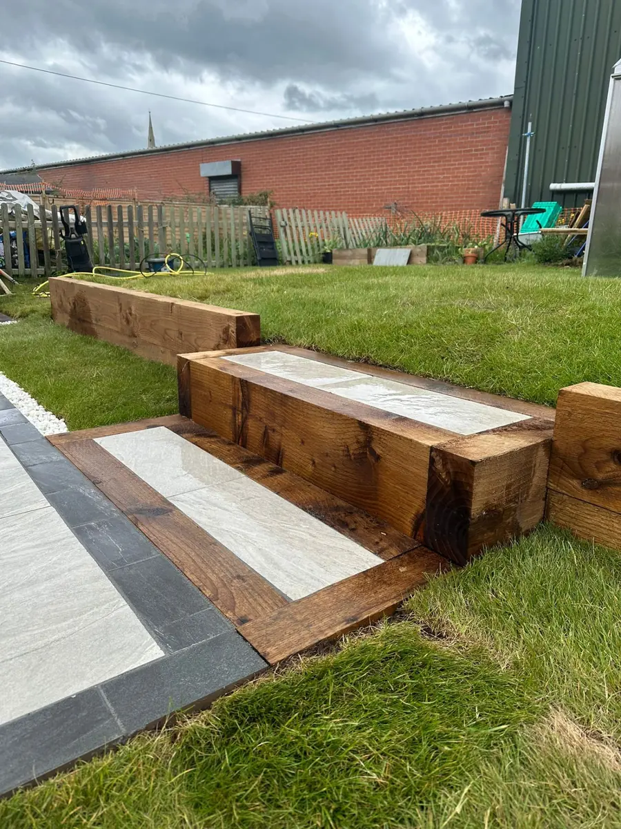 Timber sleeper steps with porcelain paving inlay leading from the lawn up onto the new patio